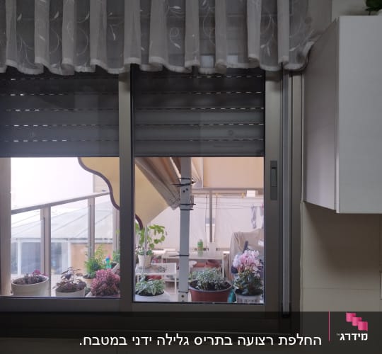 תריסים סגורים בחלון מטבח עם וילון לבן